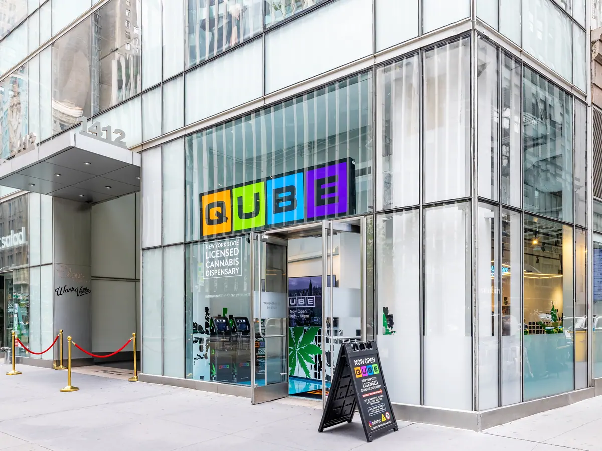 The Qube storefront at 1412 Broadway, a glass corner shop with the four-color QUBE sign over the door